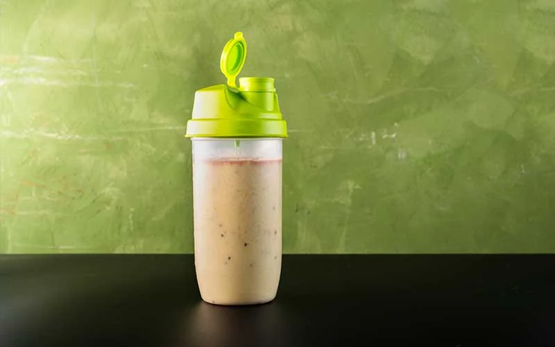 Meal Replacement Shake in a shaker on a green background